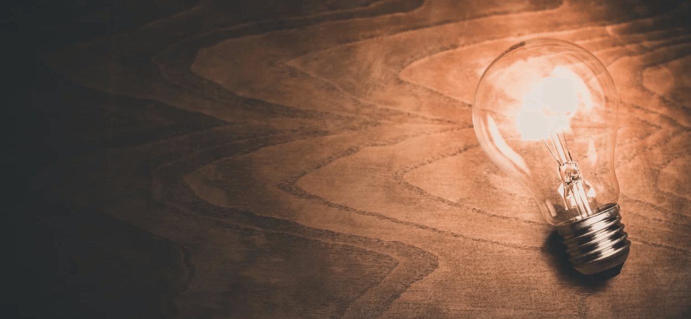 Lit lightbulb on a wooden background